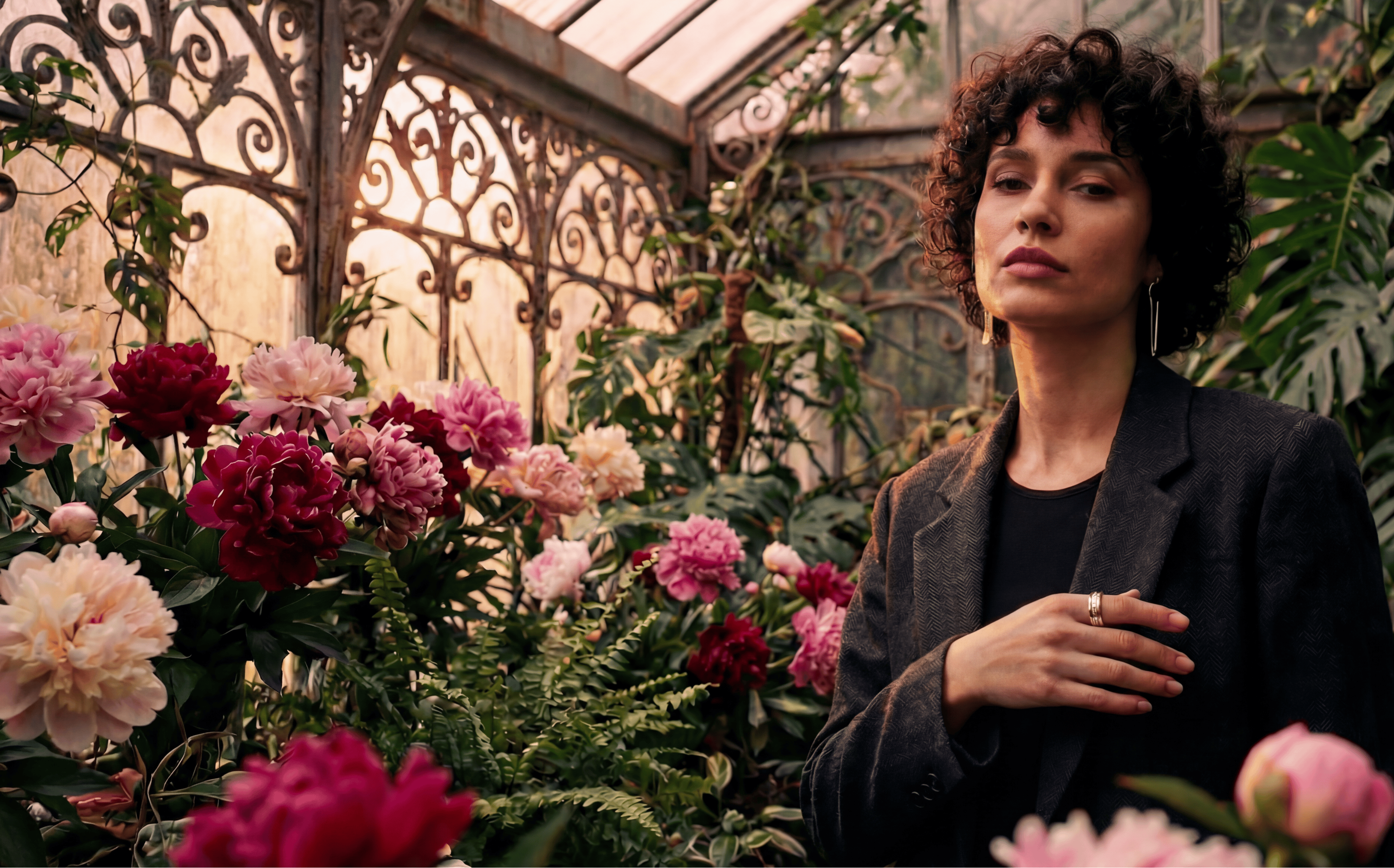 Woman wearing a fashionable smart ring standing amidst flowers in a greenhouse