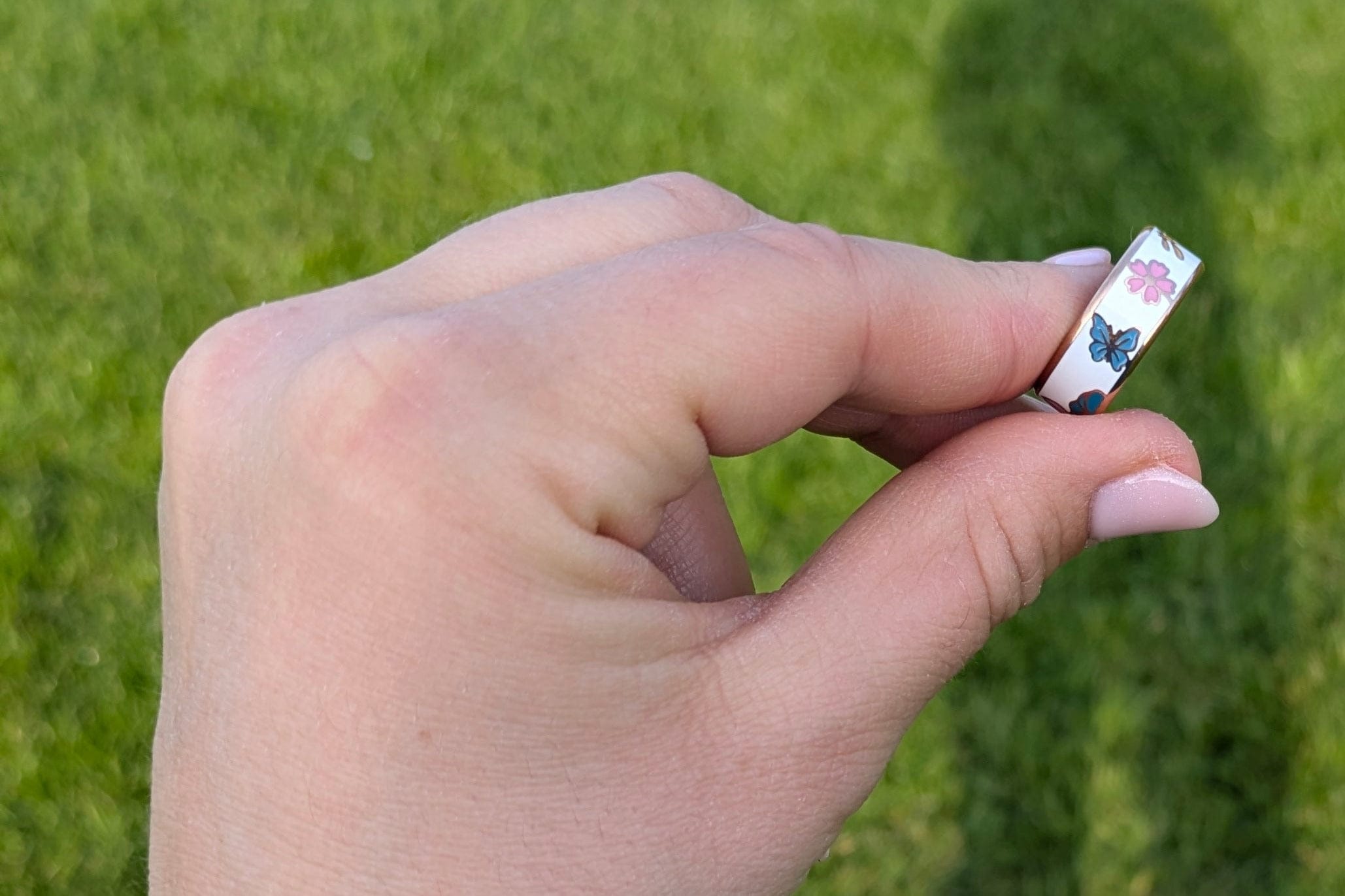 hand holding floral smart ring with grass in the background