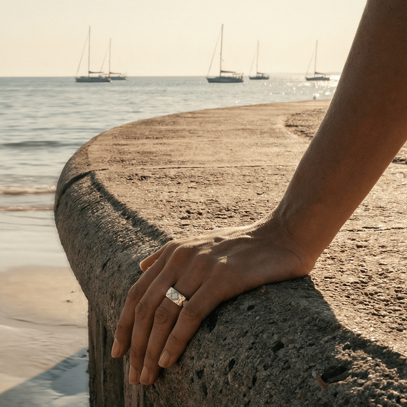 Hand wearing Nala fashionable smart ring jewellery white and gold pattern on harbour
