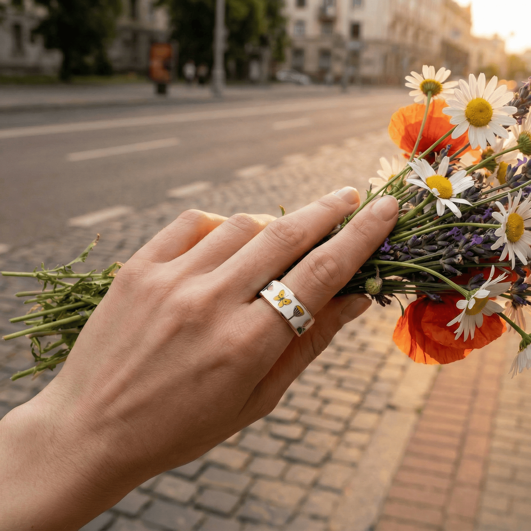 Hand holding a bouquet of wildflowers on a city street.